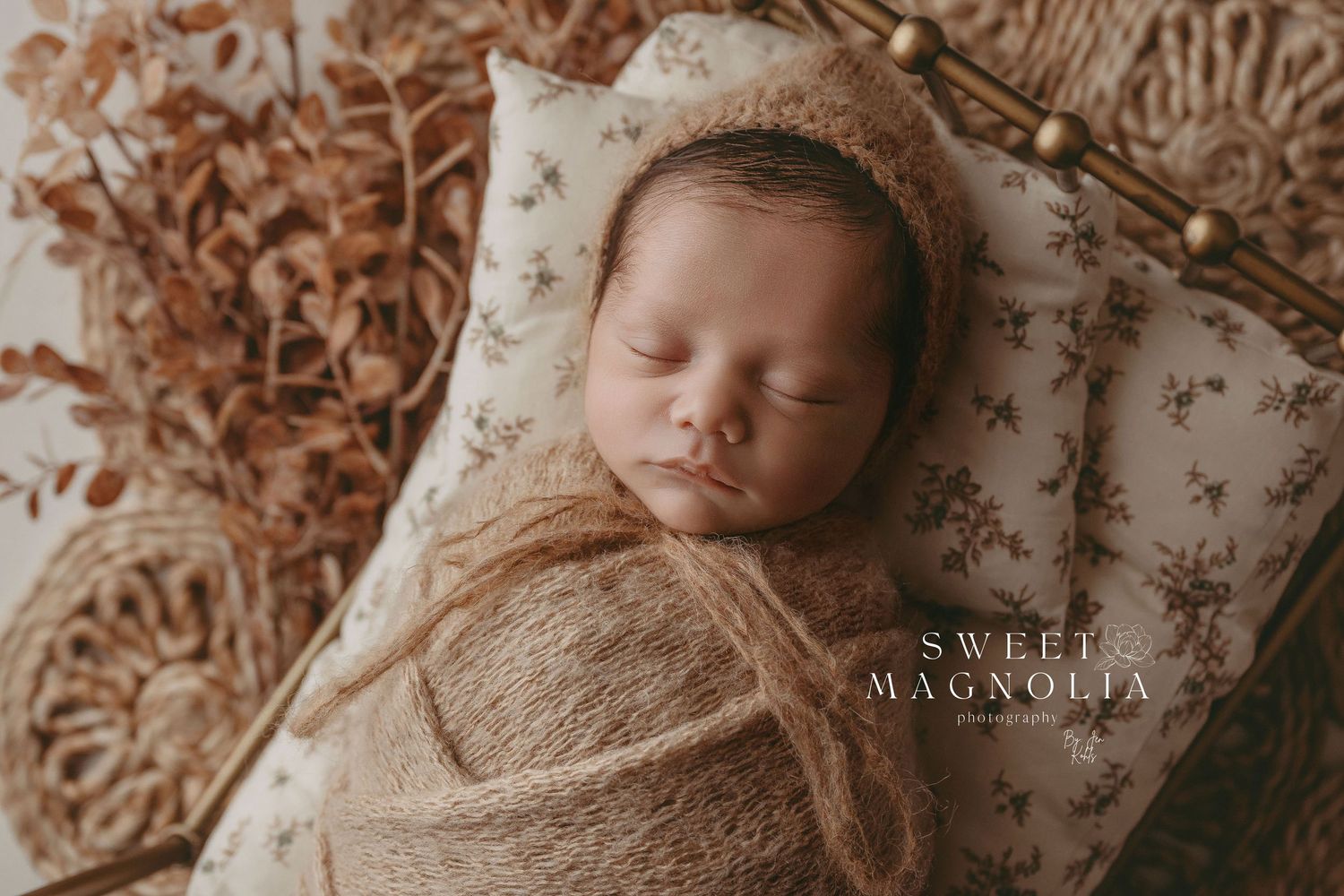 Gentle sepia-toned newborn portrait with vintage floral patterns and natural textures.