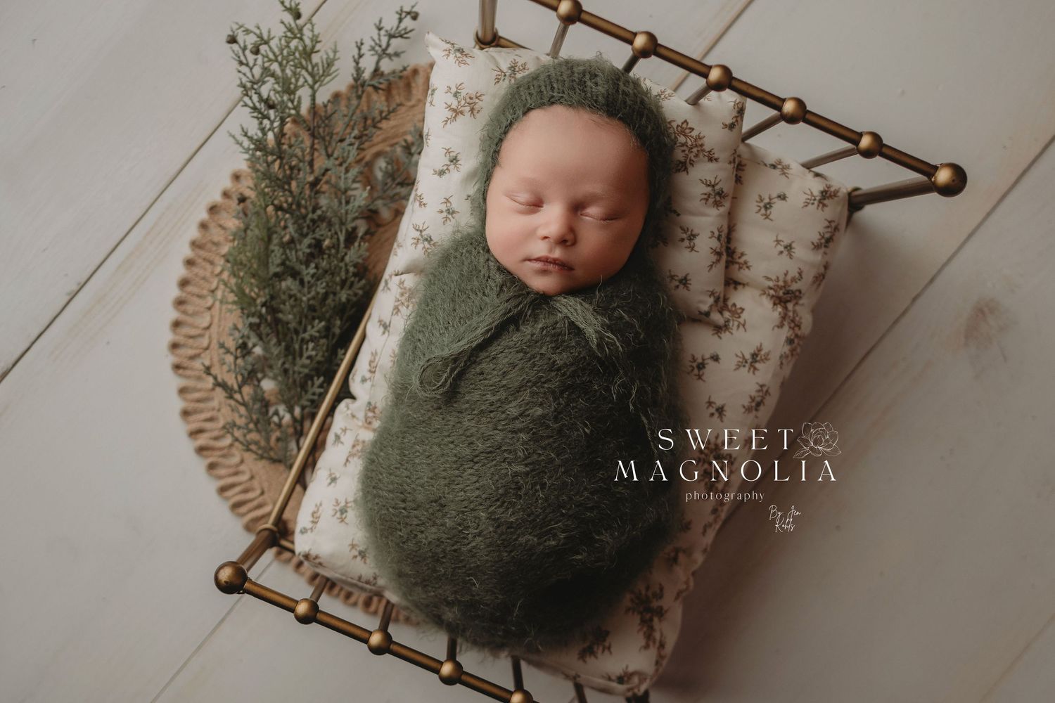 Rustic newborn photography setup with natural wood and green tones.