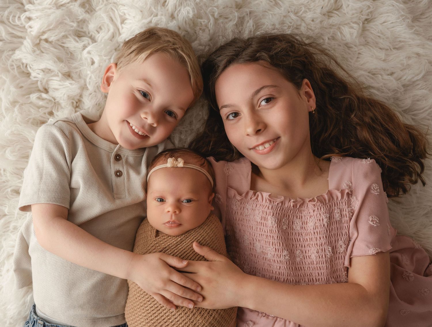 Gentle lifestyle portrait on cream textured backdrop with soft natural lighting.