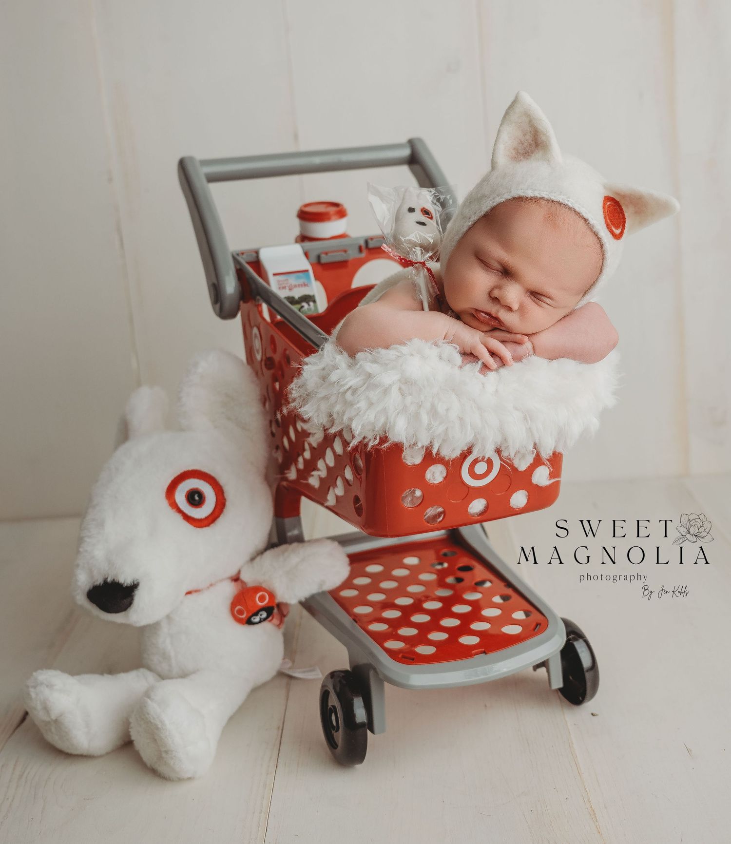 Whimsical newborn photography with red and white Target-themed props and decor.