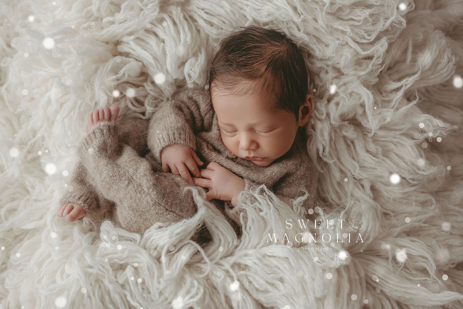 Newborn photography session with baby lying on soft white textured blanket with delicate lighting.