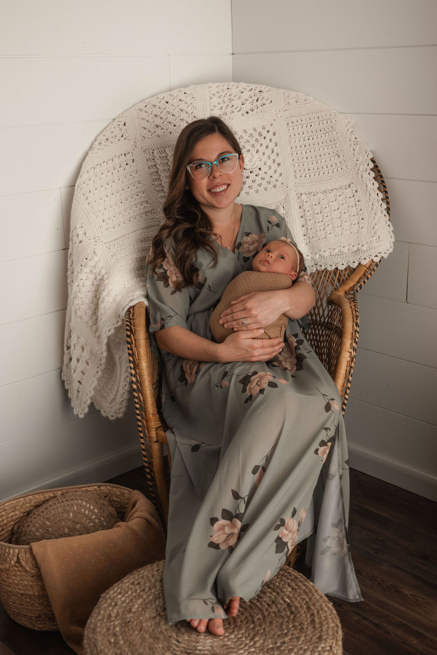 Tender lifestyle portrait session in wicker chair against white macrame wall hanging.