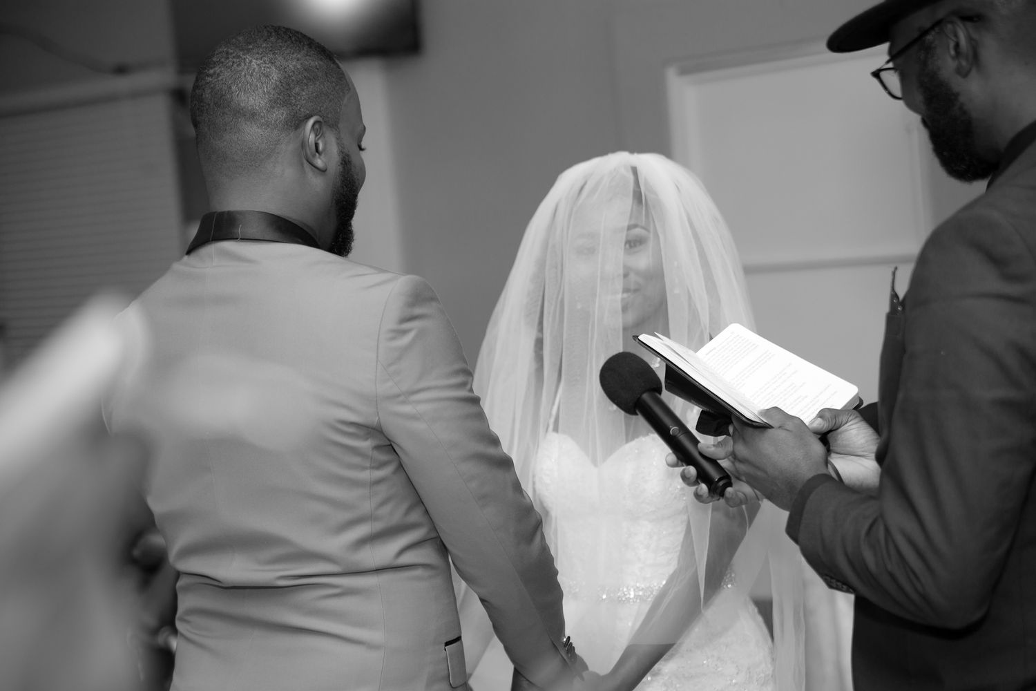 Black and white photo of a bridal ceremony with attendants reading from books.