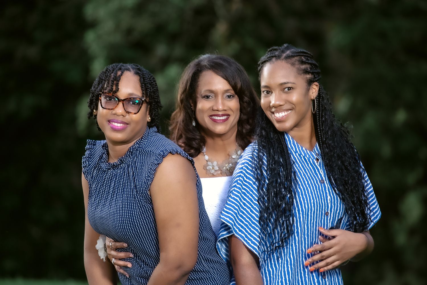 Three women in coordinated blue outfits smile together during an outdoor photo session.