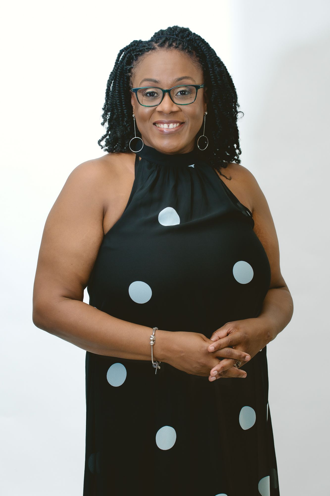Elegant portrait of someone wearing a black polka dot halter dress and glasses.