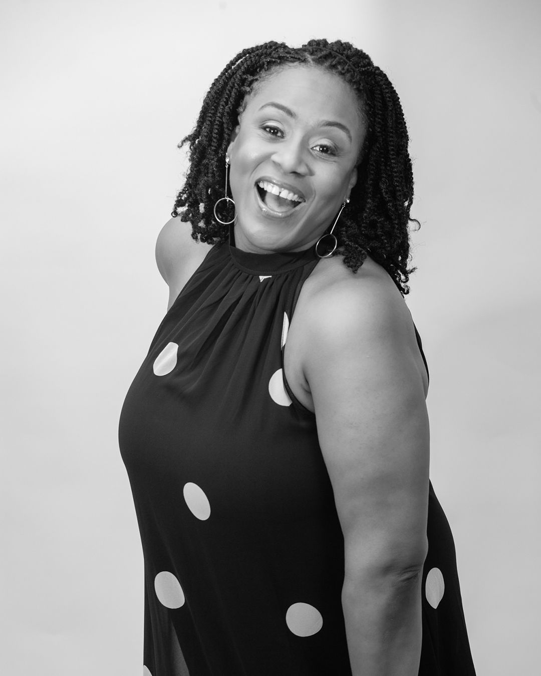 A black and white portrait of a person in a polka dot dress with braided hair.