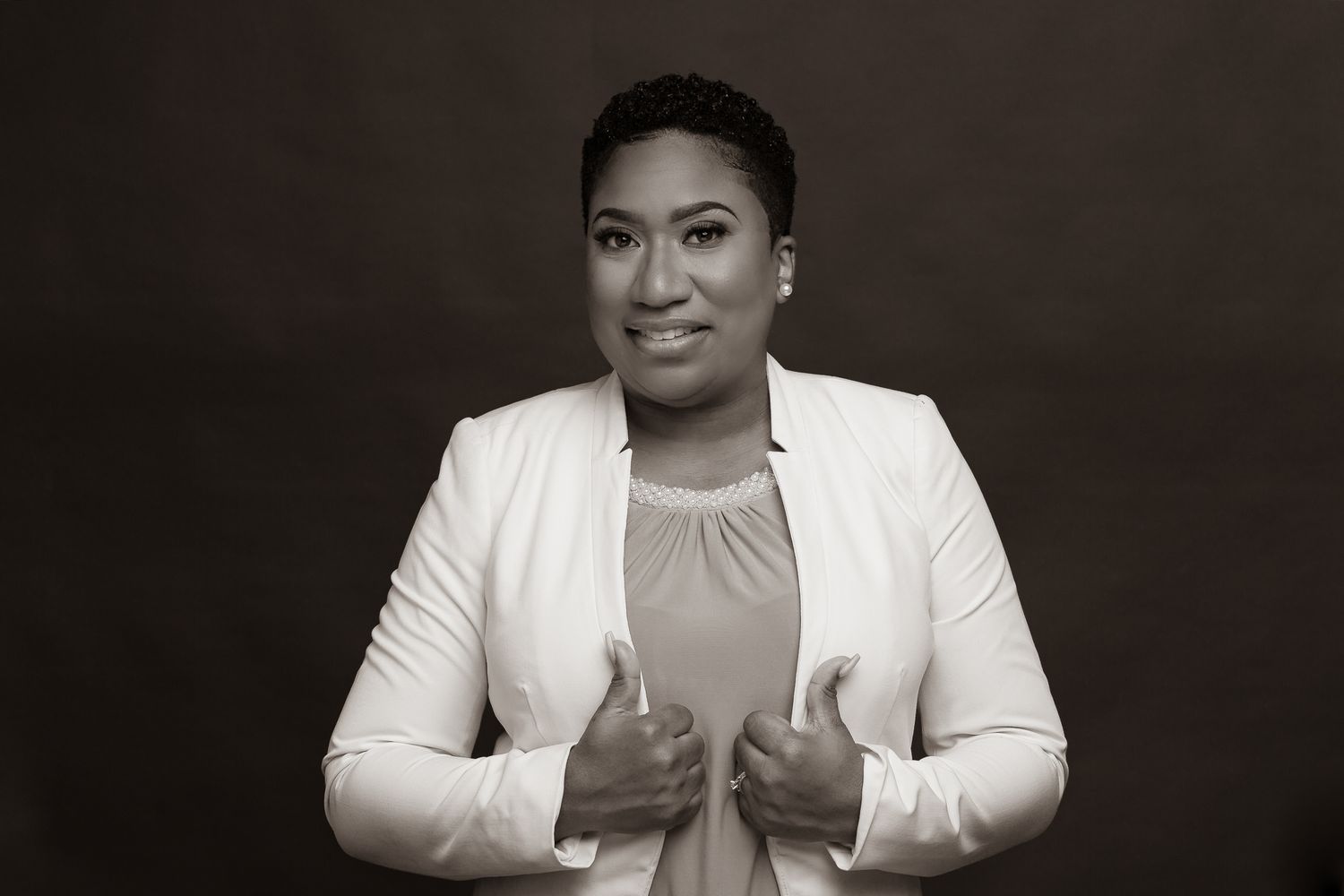 Black and white professional portrait in white blazer showing confident pose.