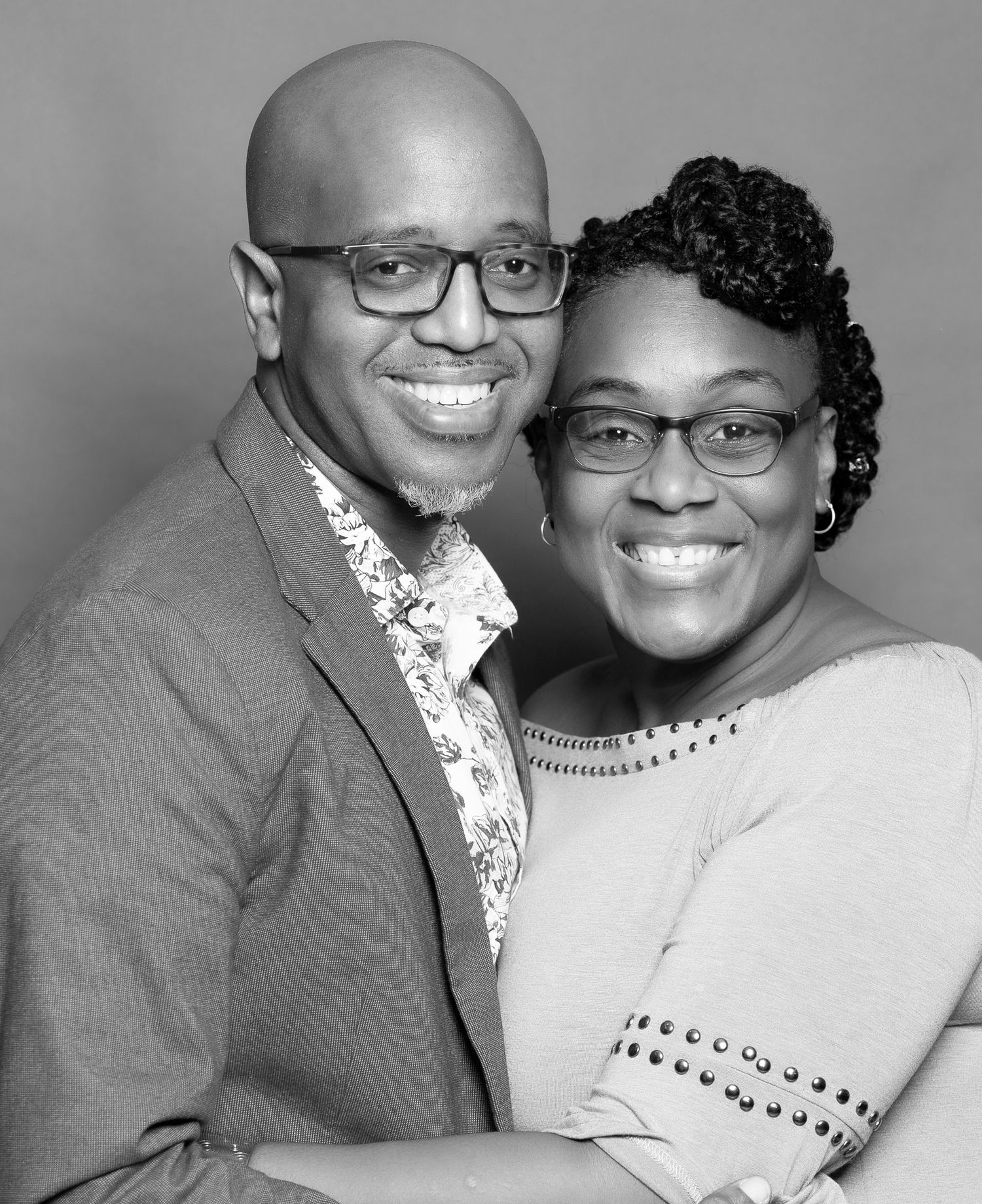 A formal studio portrait in black and white of a couple wearing dressy attire.