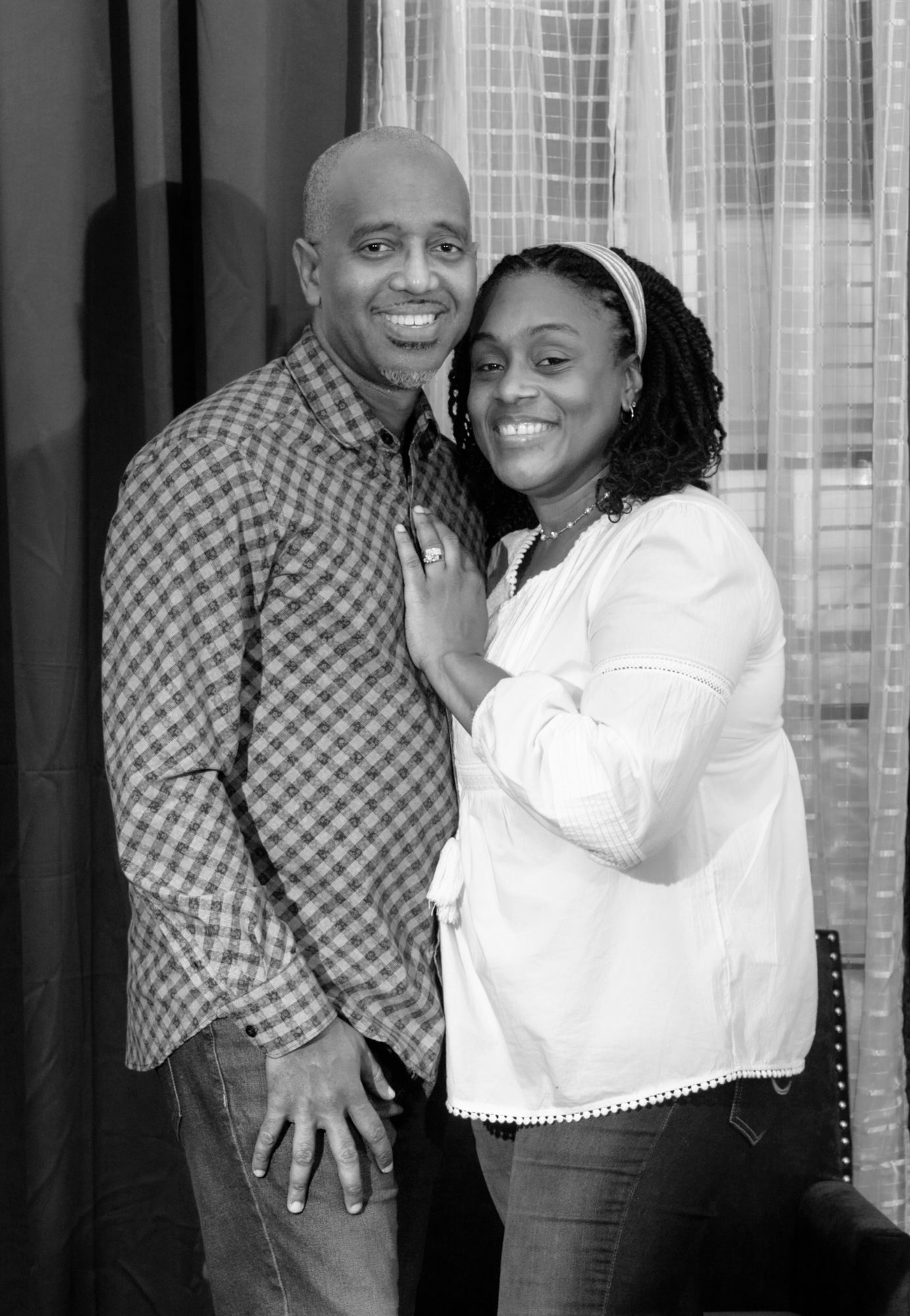 A couple shares a warm embrace while posing together for a black and white portrait.