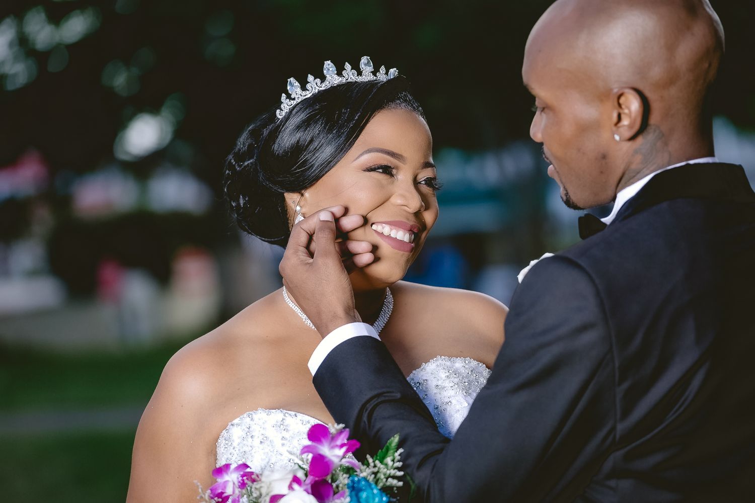 Tender wedding moment captured as newlyweds share an emotional touch outdoors.