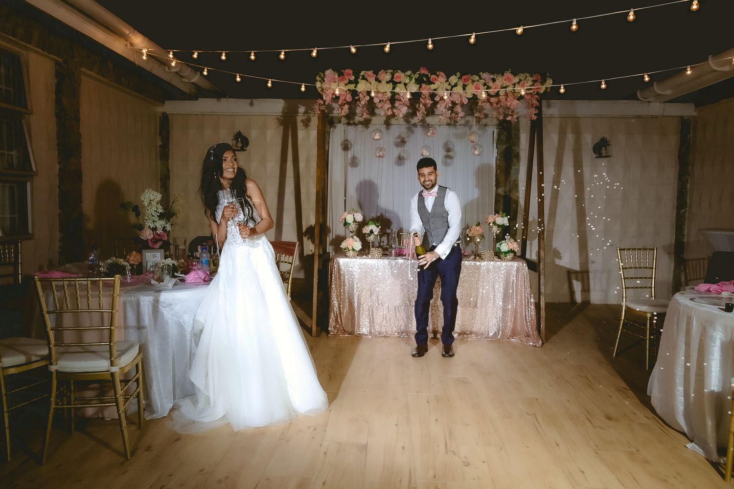 Elegant wedding reception venue with string lights, floral arch and dressed tables.