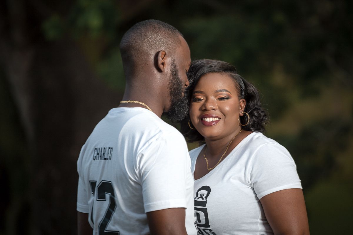 A couple wearing matching white shirts share a joyful moment together outdoors.