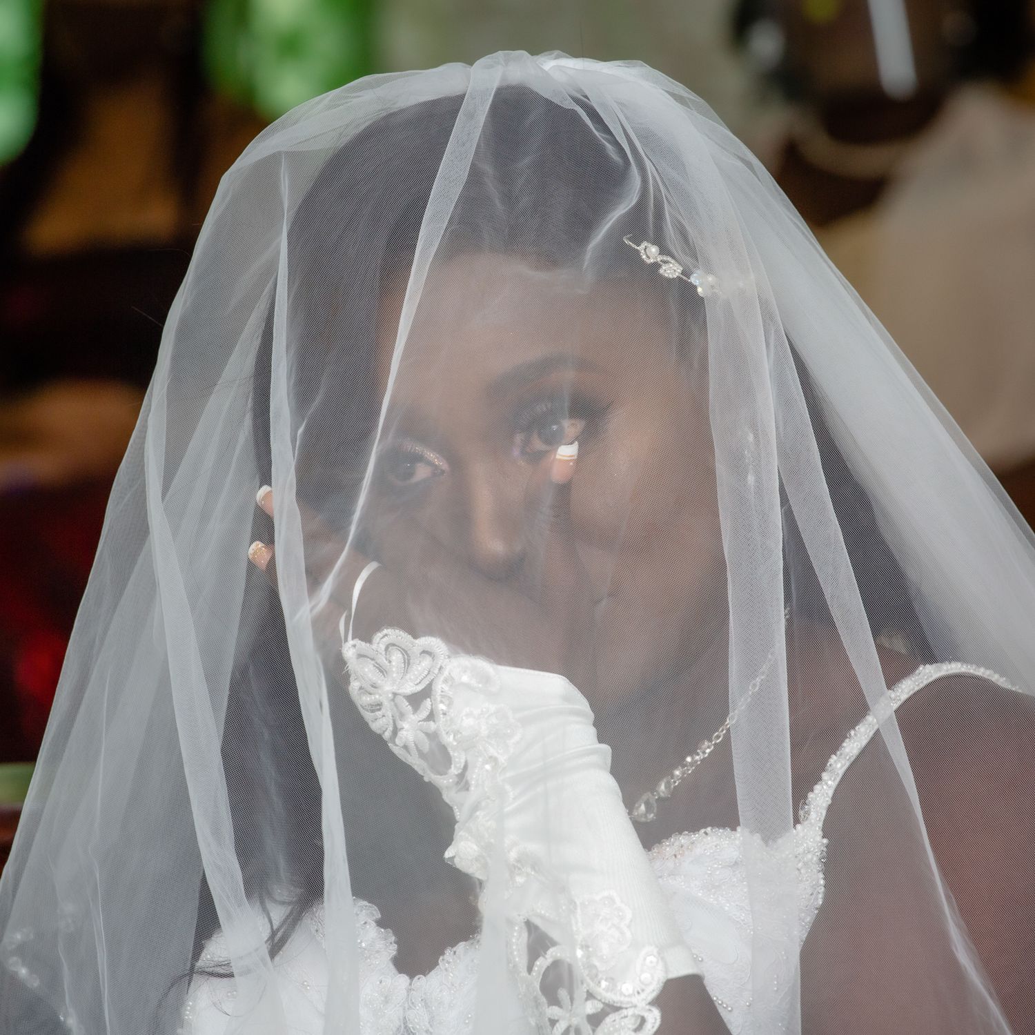 A dreamy bridal portrait shows a bride's gentle smile through her delicate lace veil.
