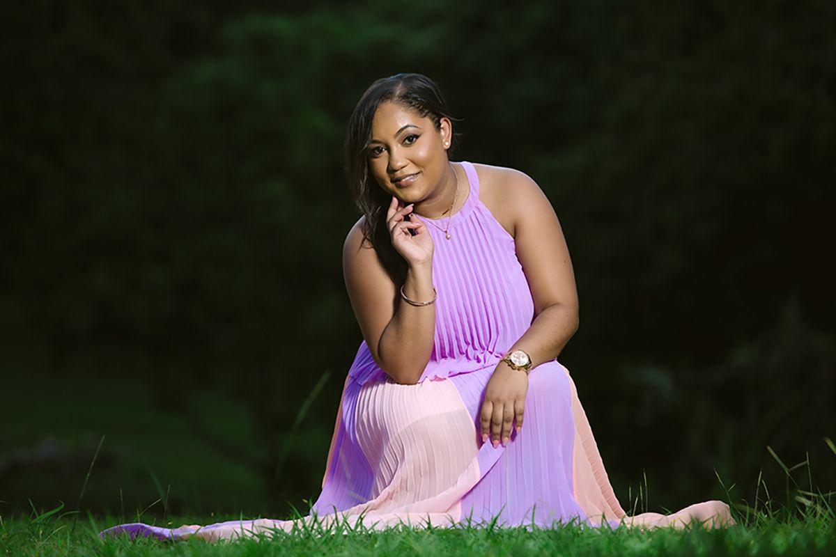 Portrait of someone in a flowing pink dress posed gracefully on grass.