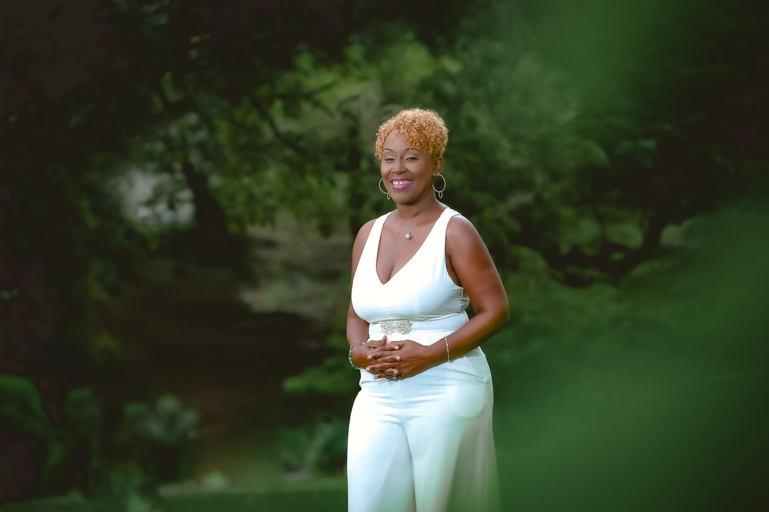 Portrait of someone in white athletic wear standing against blurred green foliage.