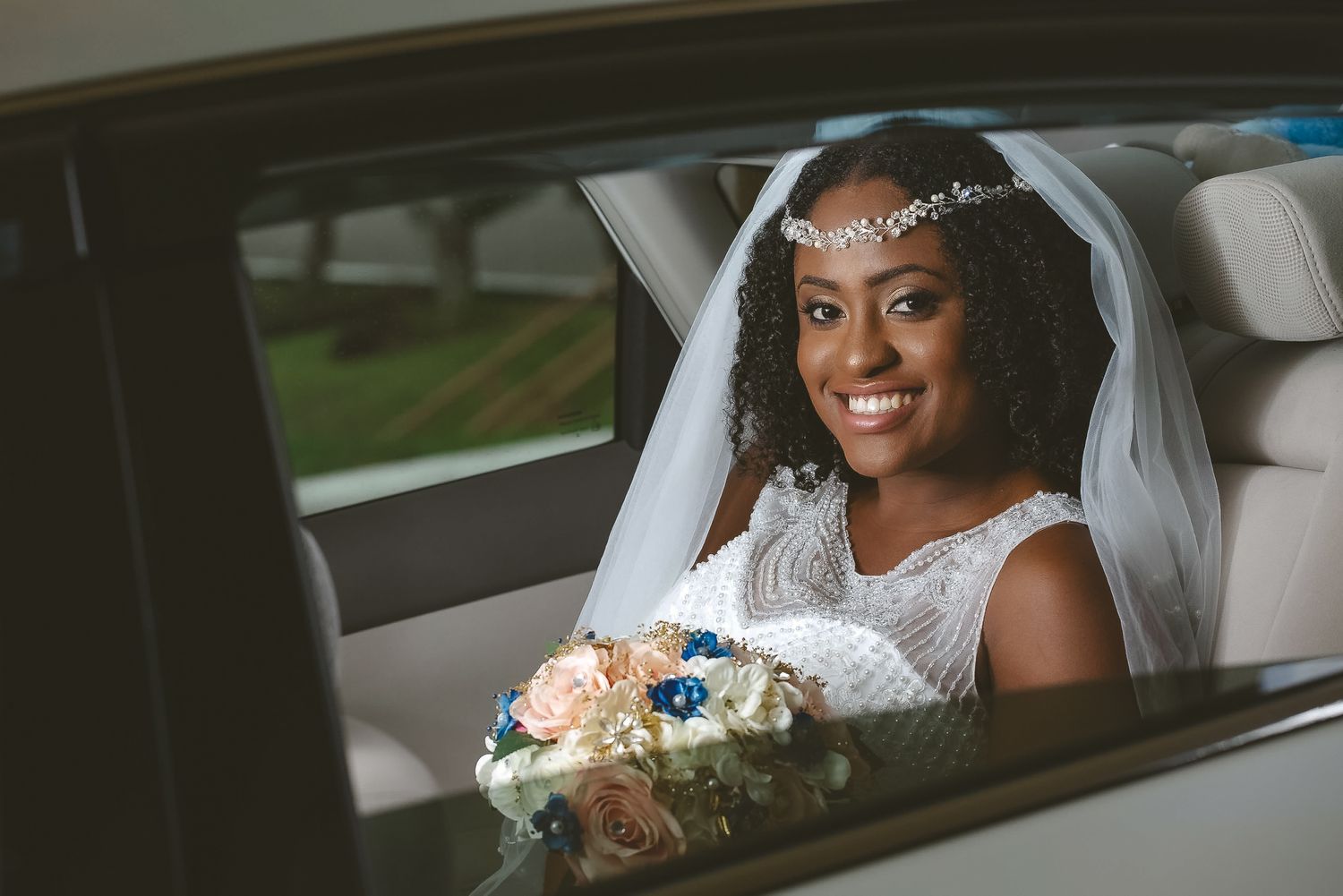 Radiant bride sitting in a car with a beautiful bouquet on her wedding day.