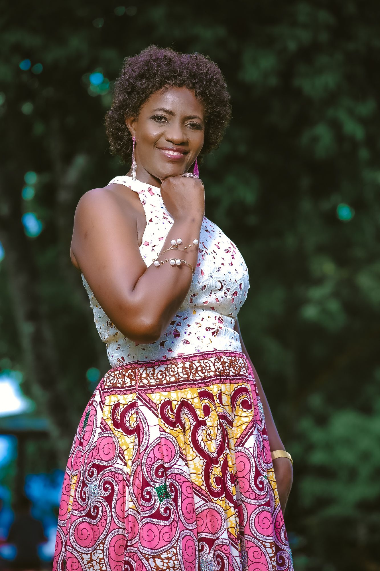 Woman in floral halter top and pink patterned skirt poses outdoors.