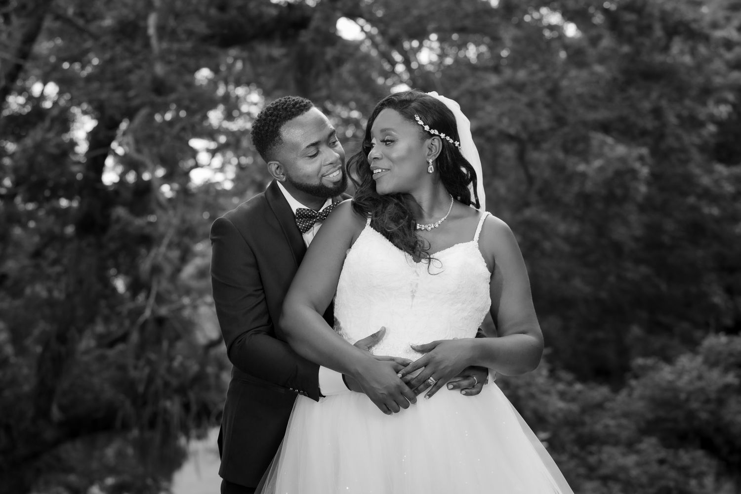 Black and white portrait of a couple embracing during their outdoor wedding photoshoot.