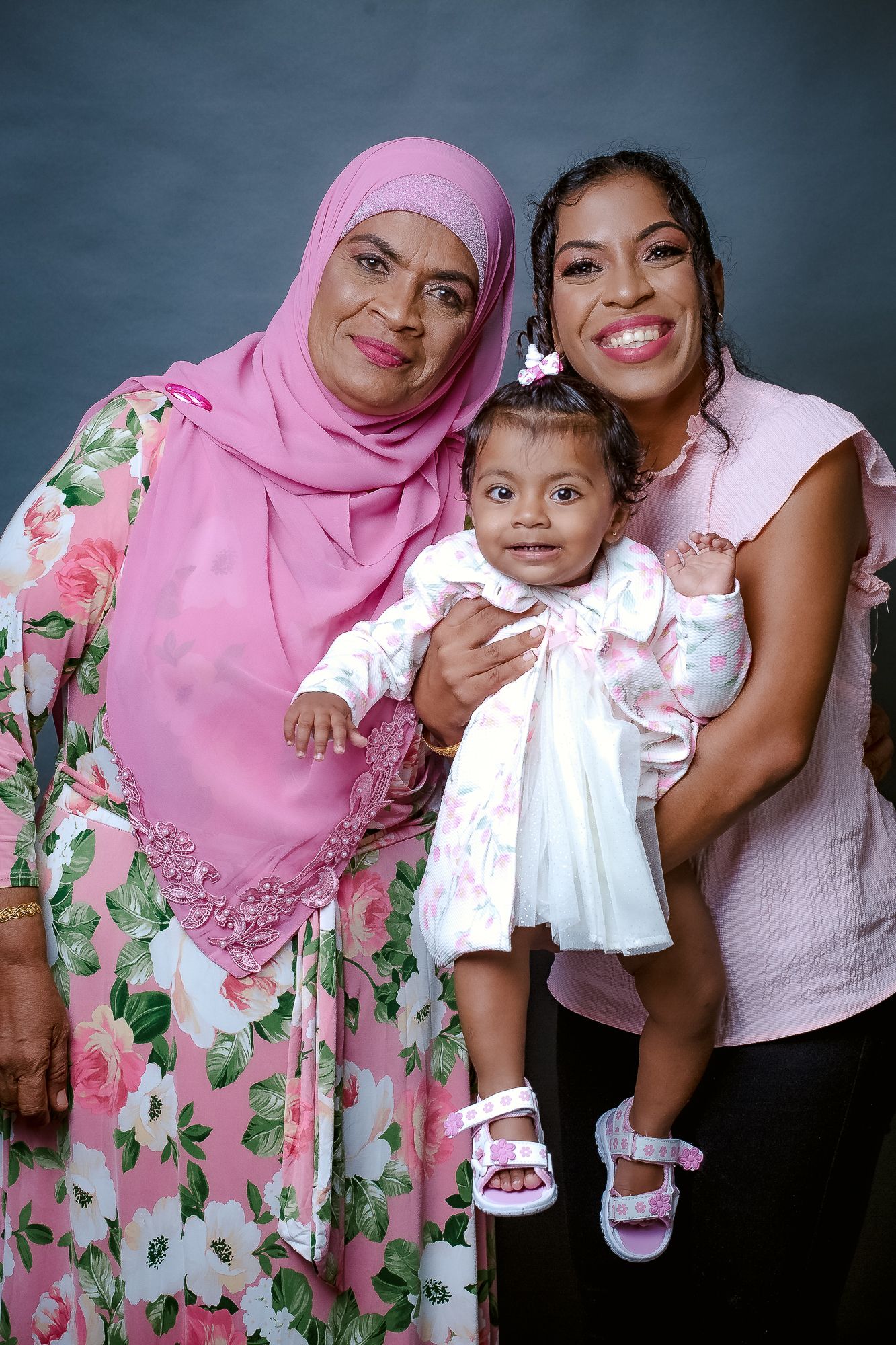 A multi-generational family photo featuring traditional dress and a small child in white.