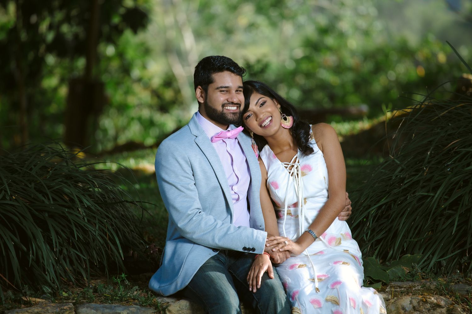 Couple sharing a joyful moment together while sitting outdoors in a natural garden setting.