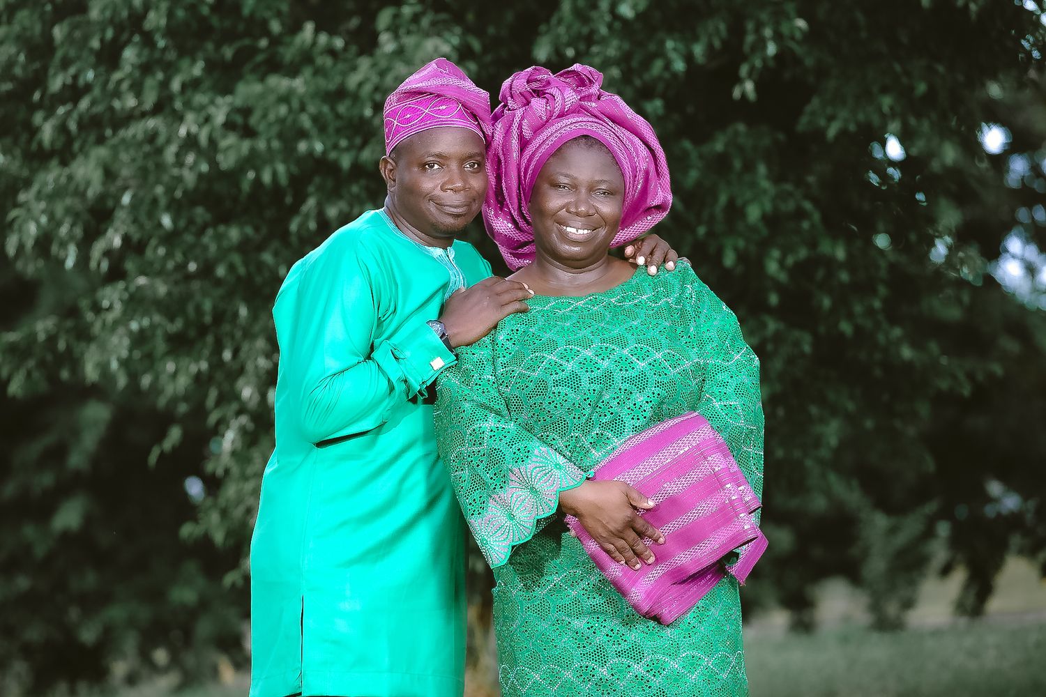 Couple in traditional African attire with bright turquoise and pink colors.