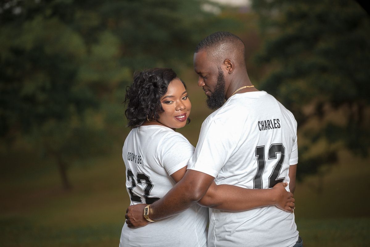 A couple wearing matching white jerseys with number 12 share an intimate moment outdoors.
