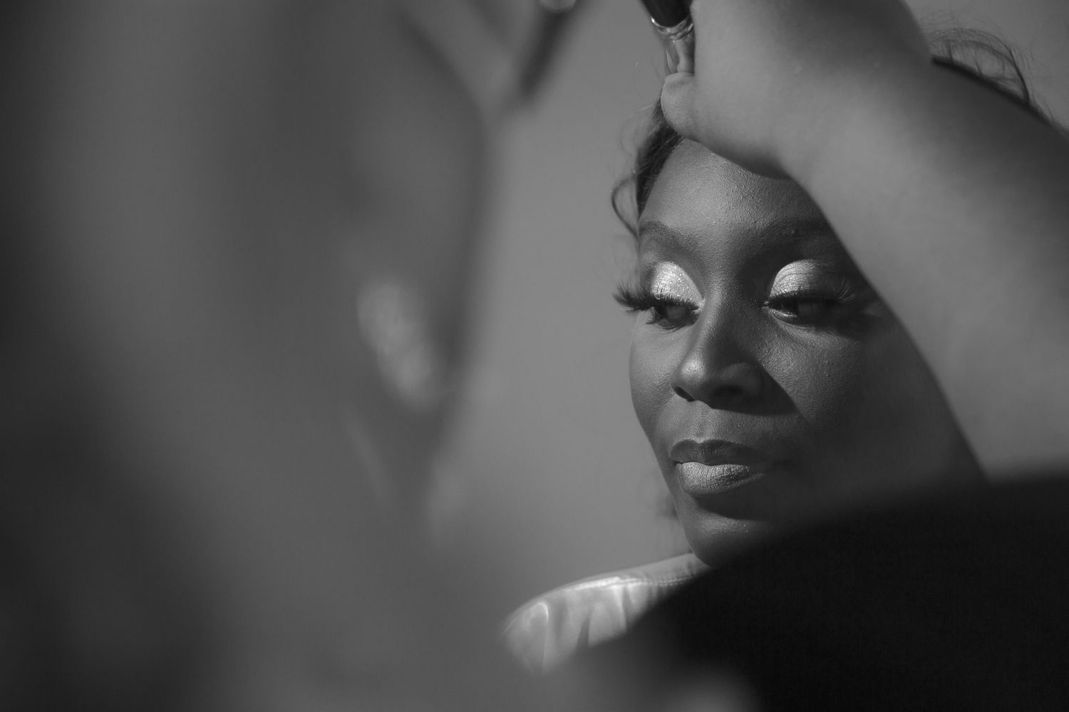 An artistic black and white bridal portrait captures preparation moments before the ceremony.