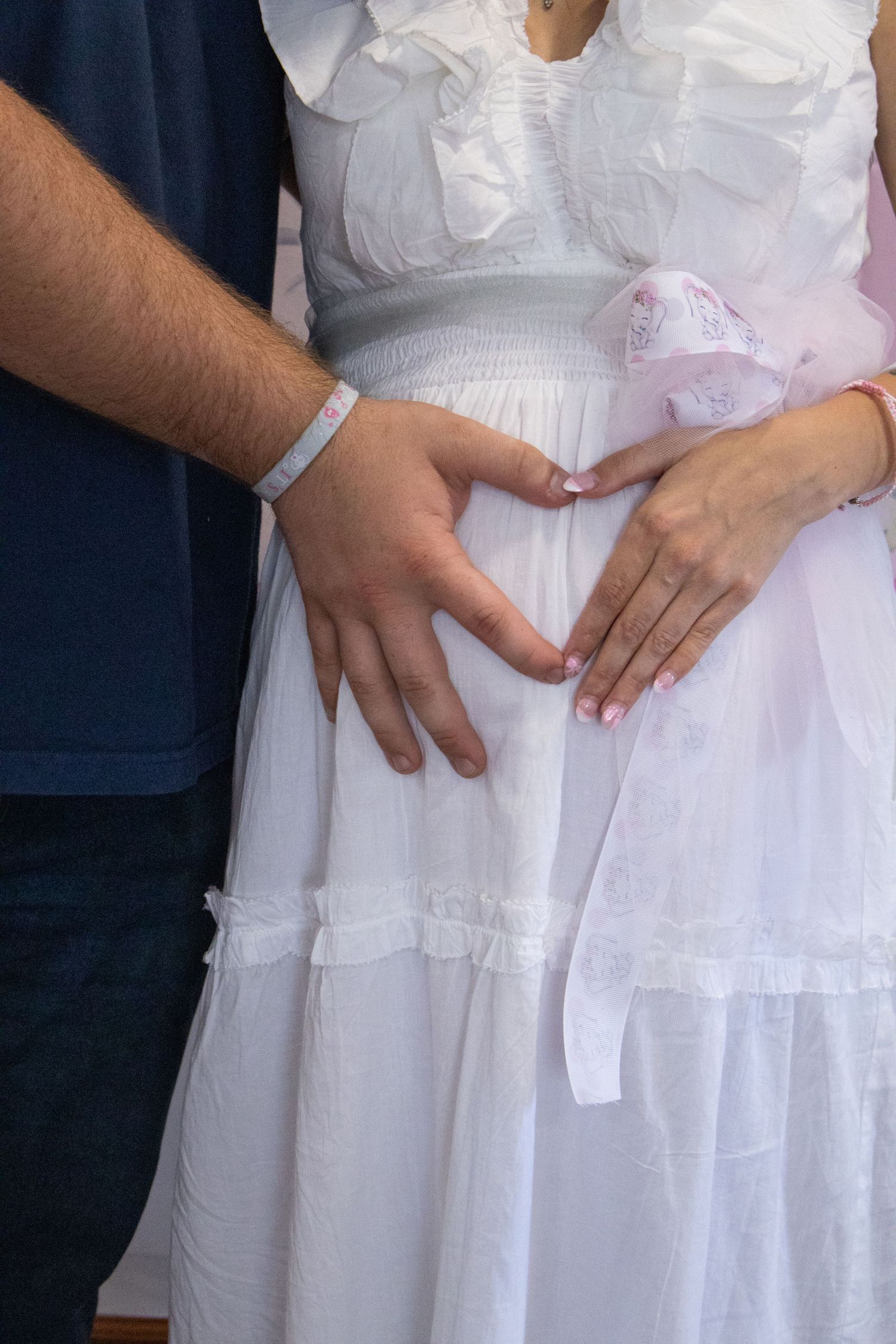 A series of hands rest on the waist area of a white dress, showing different positions in sequence.