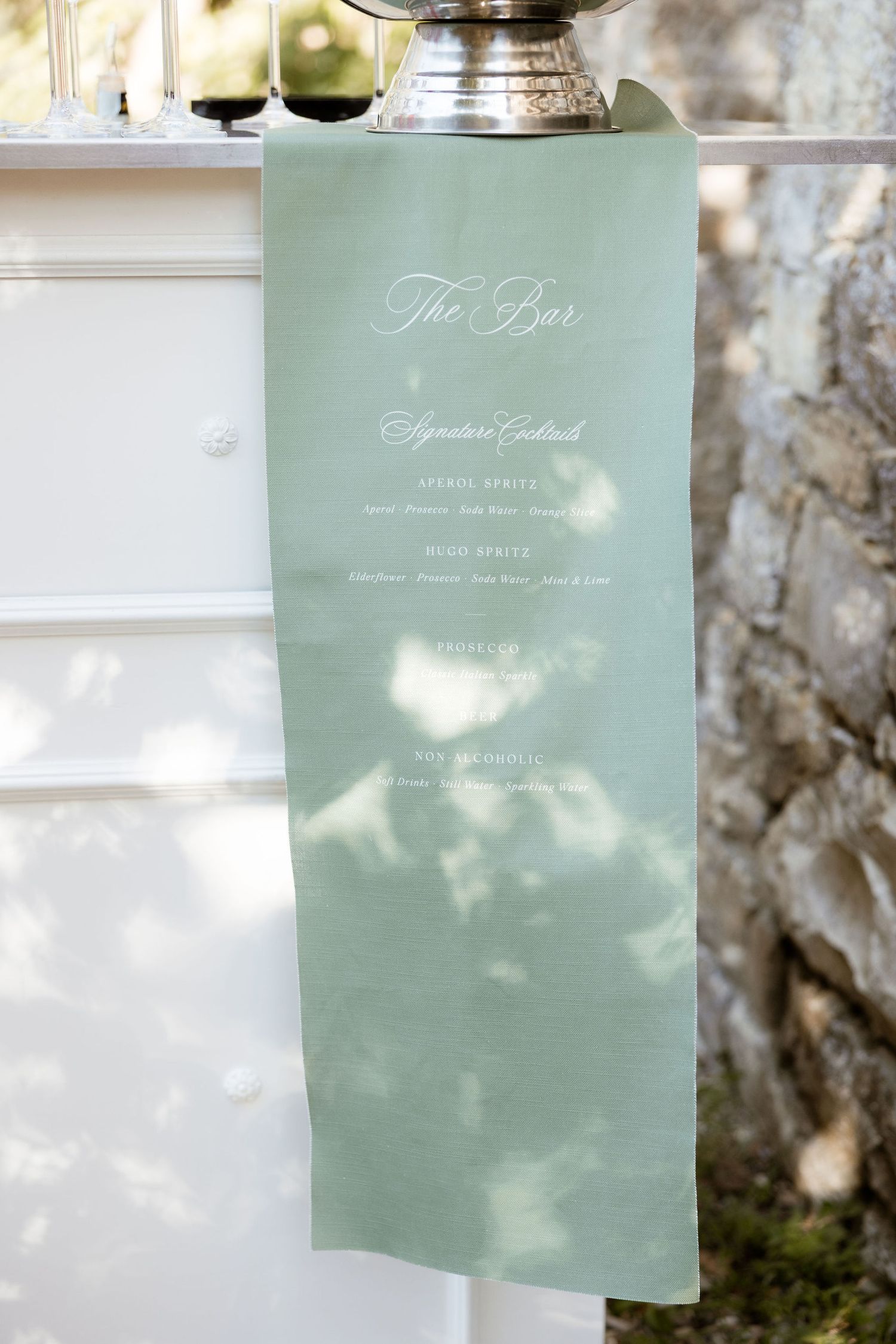 Elegant mint green wedding menu cards displayed in soft natural lighting with shadows cast across them.
