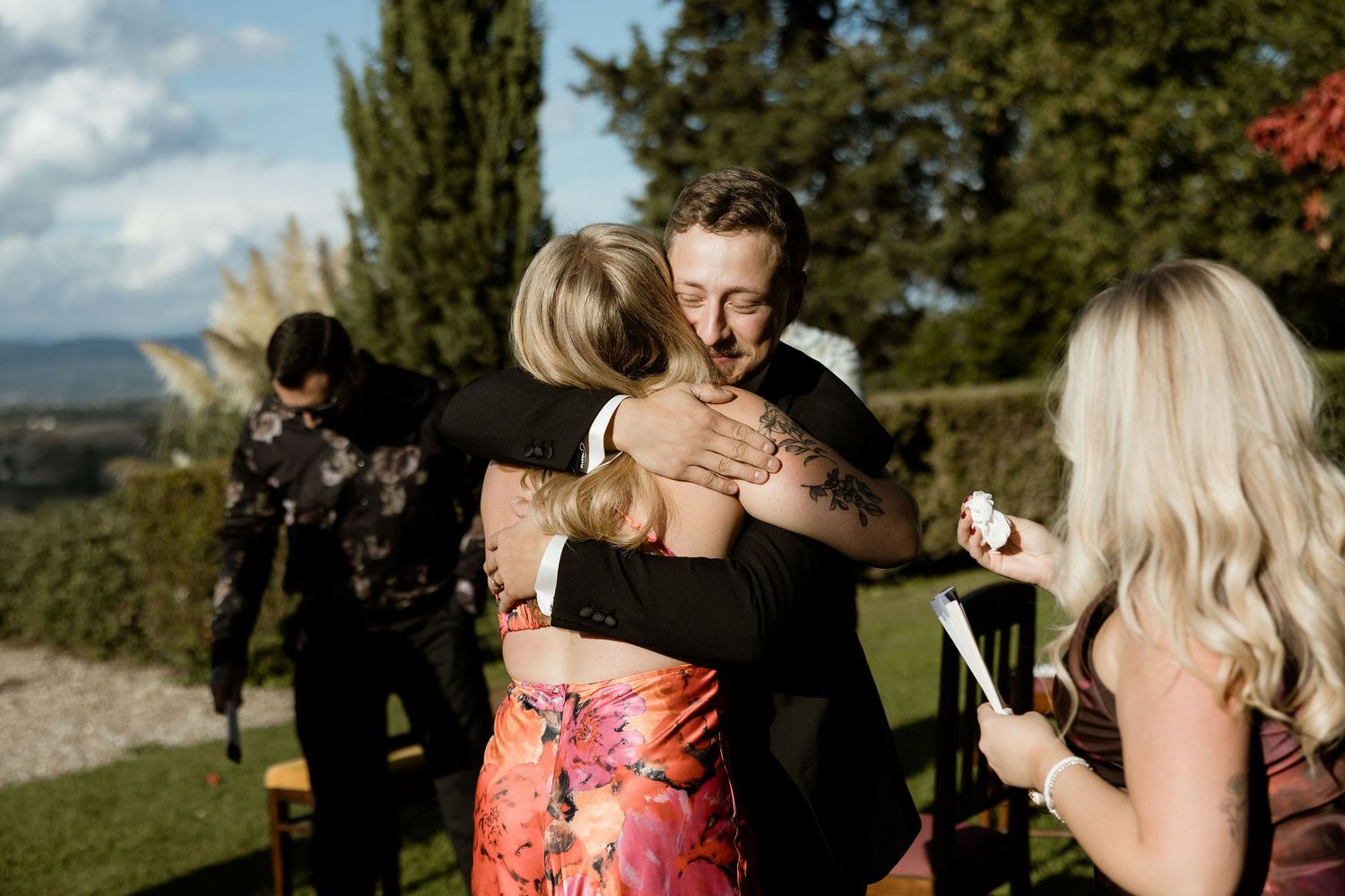 Wedding guests celebrating with hugs at an outdoor reception with mountain views.