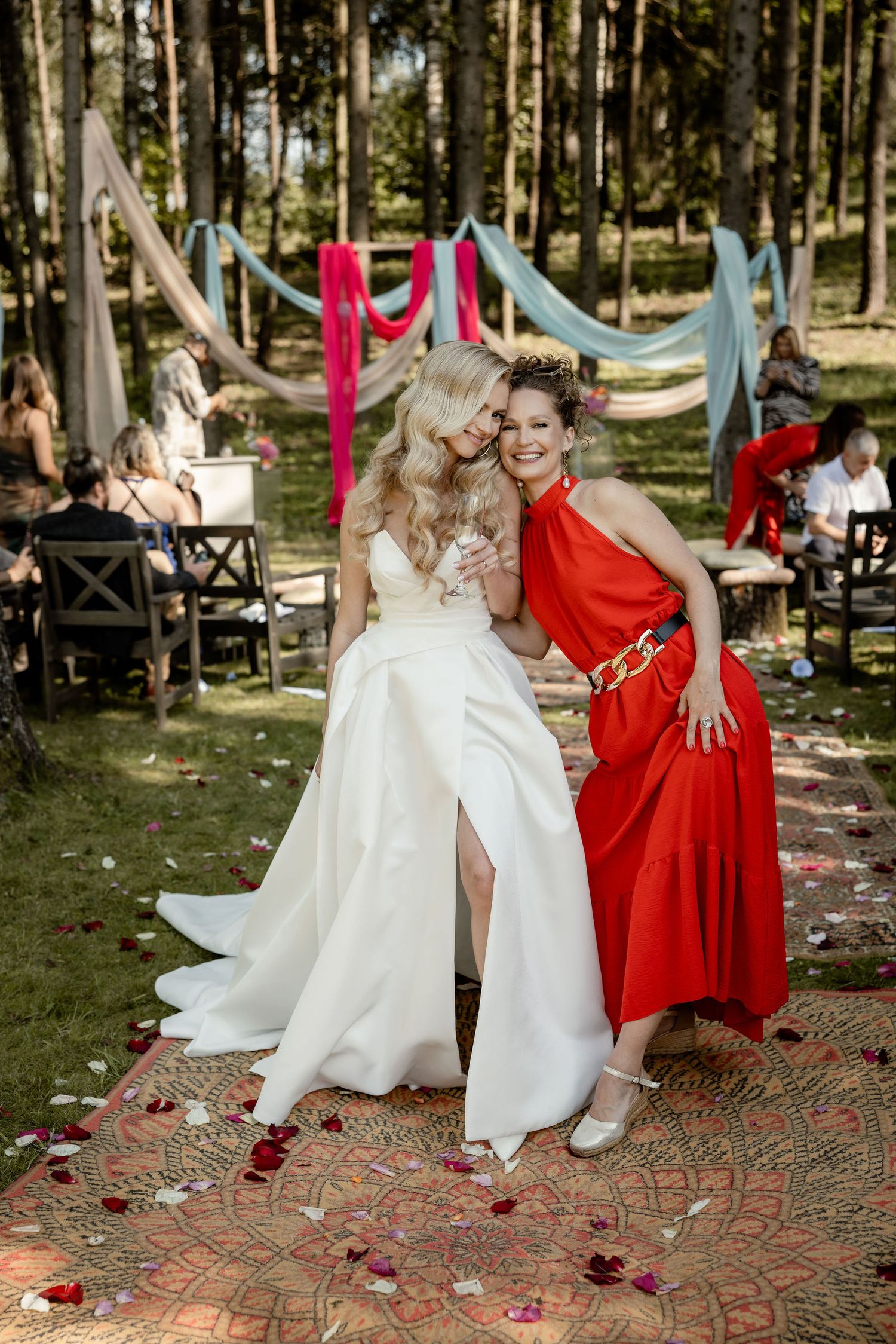 Wedding celebration in a forest setting with colorful drapes and decorative rugs.
