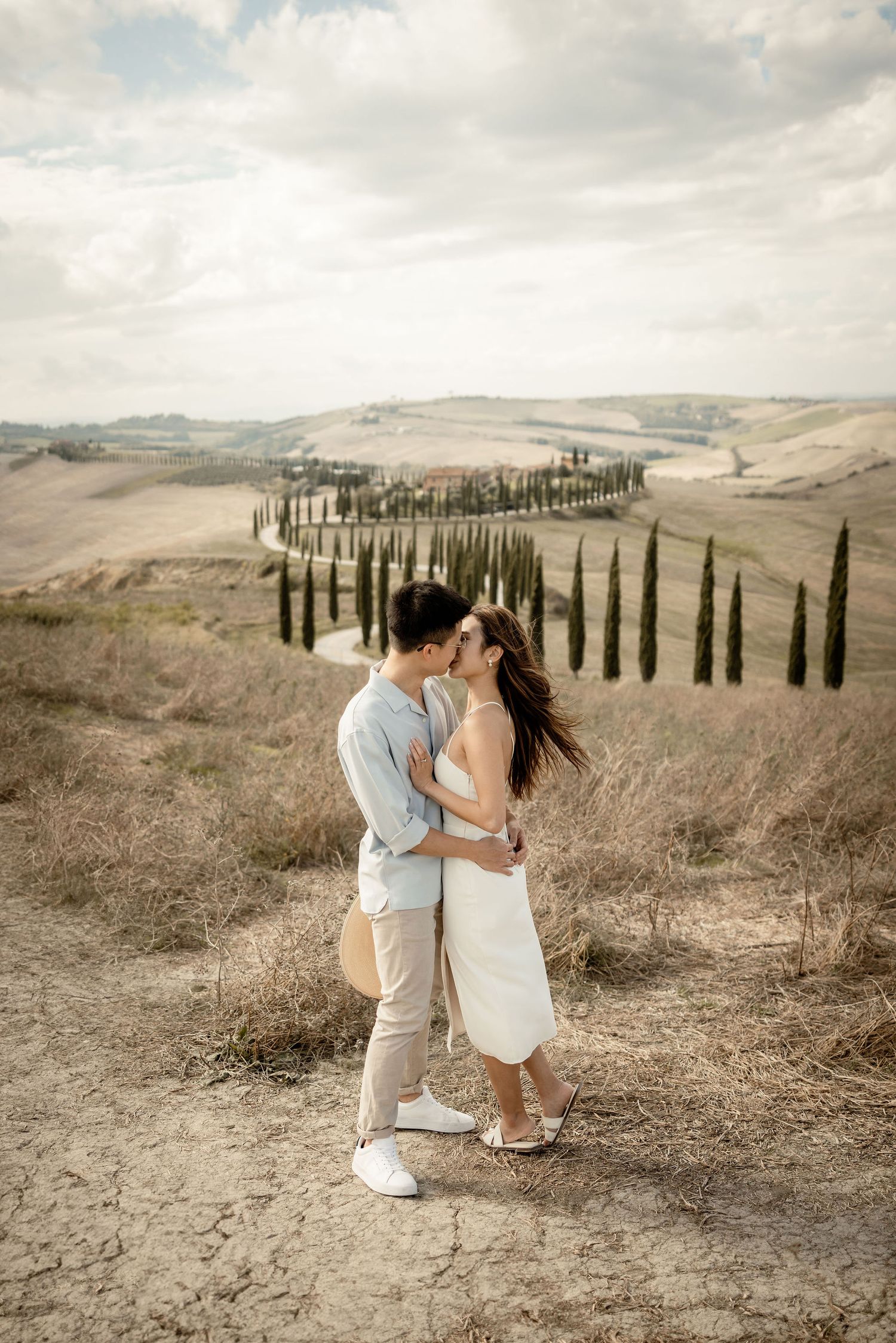 Intimate moment between couple against backdrop of Italian countryside.