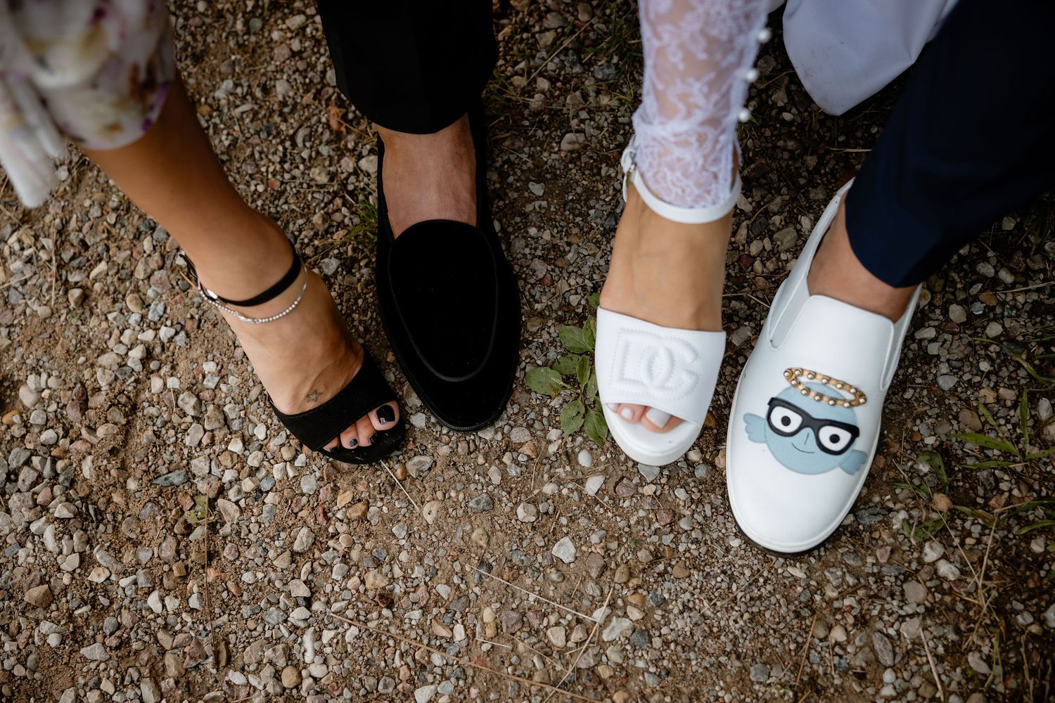 Fun wedding footwear detail showing various styles of formal shoes on gravel ground.