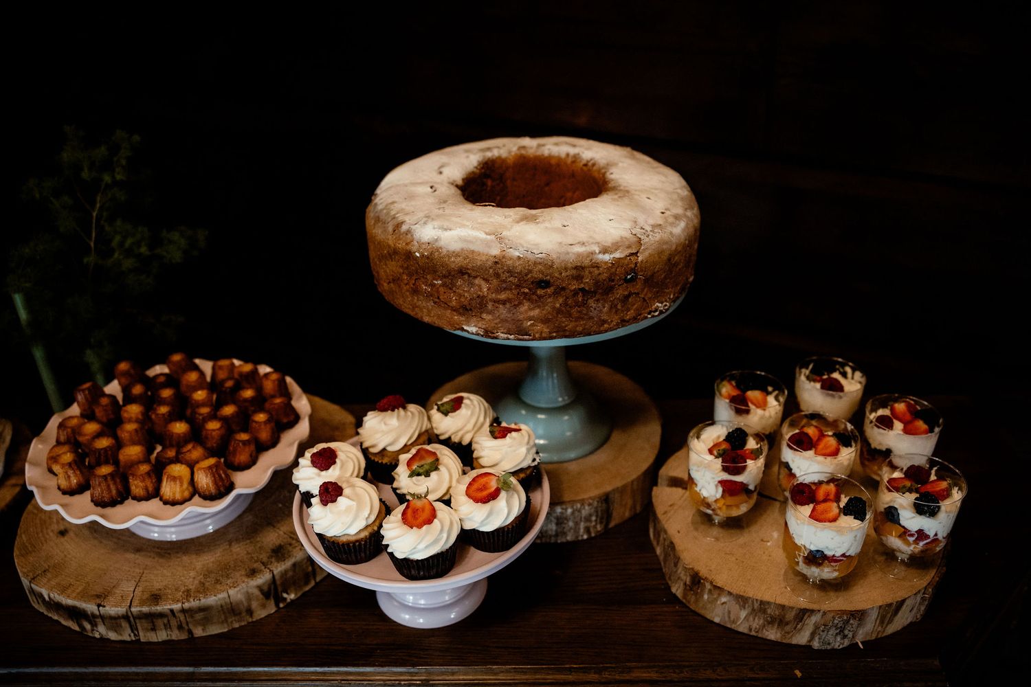 Artfully displayed desserts including donuts and cupcakes on wooden cake stands.