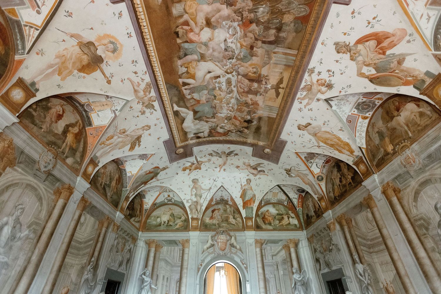 Ornate frescoed ceiling and walls in a baroque palace hall with detailed mythological paintings and architectural details.