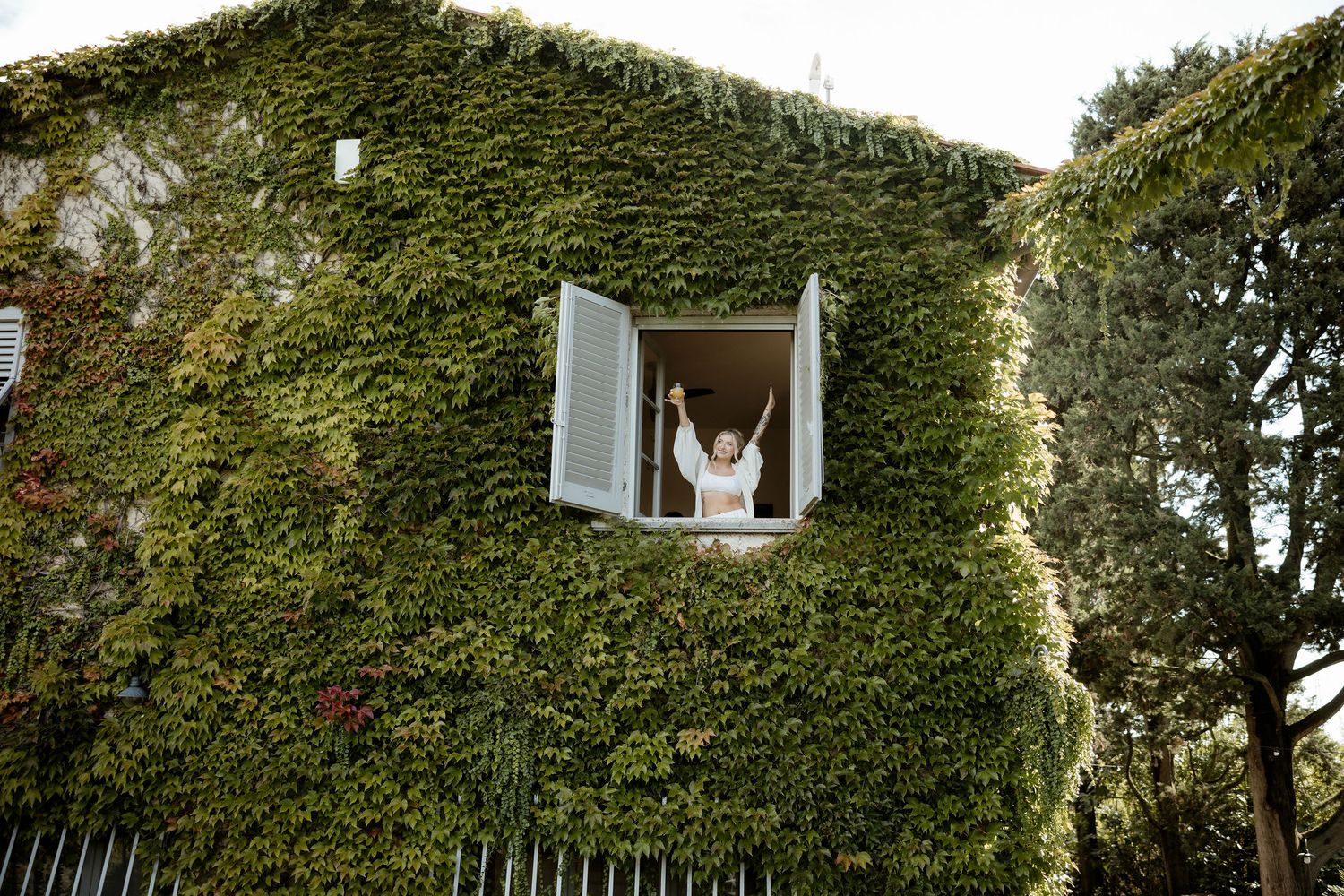 Lush green ivy covers the exterior walls and windows of a traditional stone building creating a natural facade.