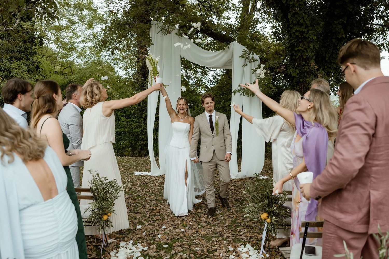 Wedding party in dusty rose and white dresses dancing and celebrating in a garden setting.