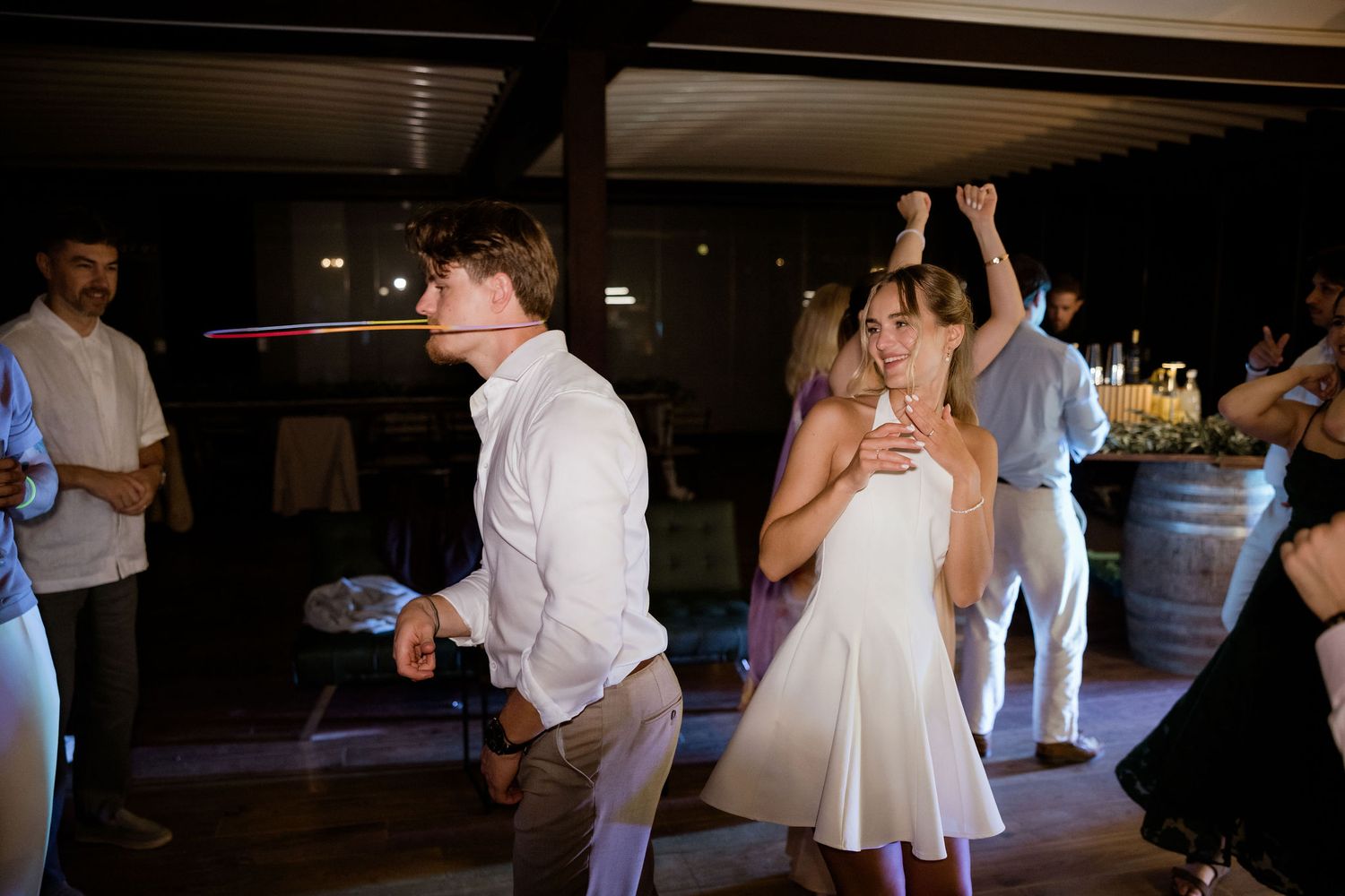 Wedding guests dance and celebrate on an illuminated dance floor at an evening reception.