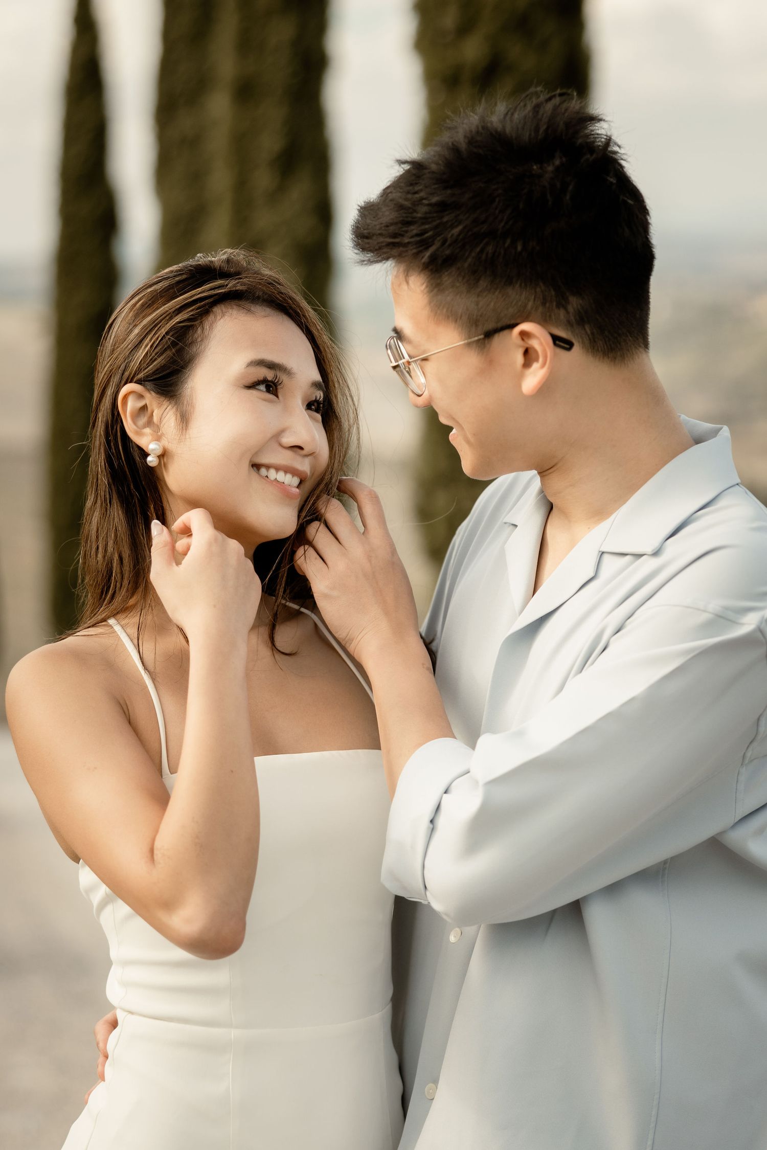 Intimate close-up of couple sharing romantic moment on Italian cypress-lined road.