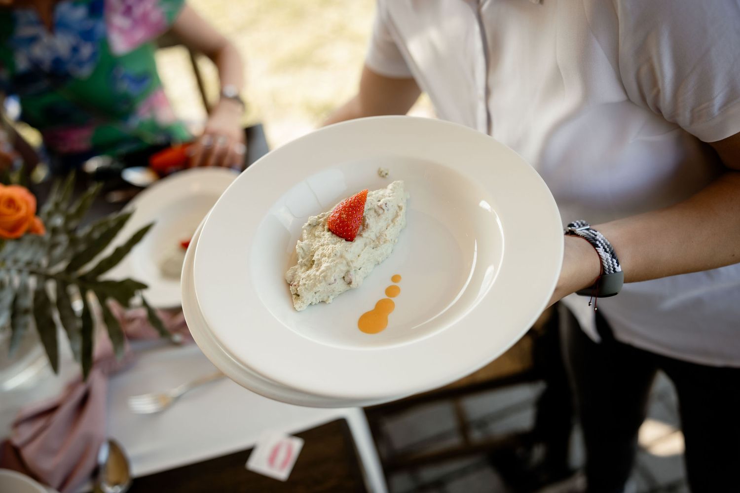 A white plate with an elegantly plated small dessert being served at an event.