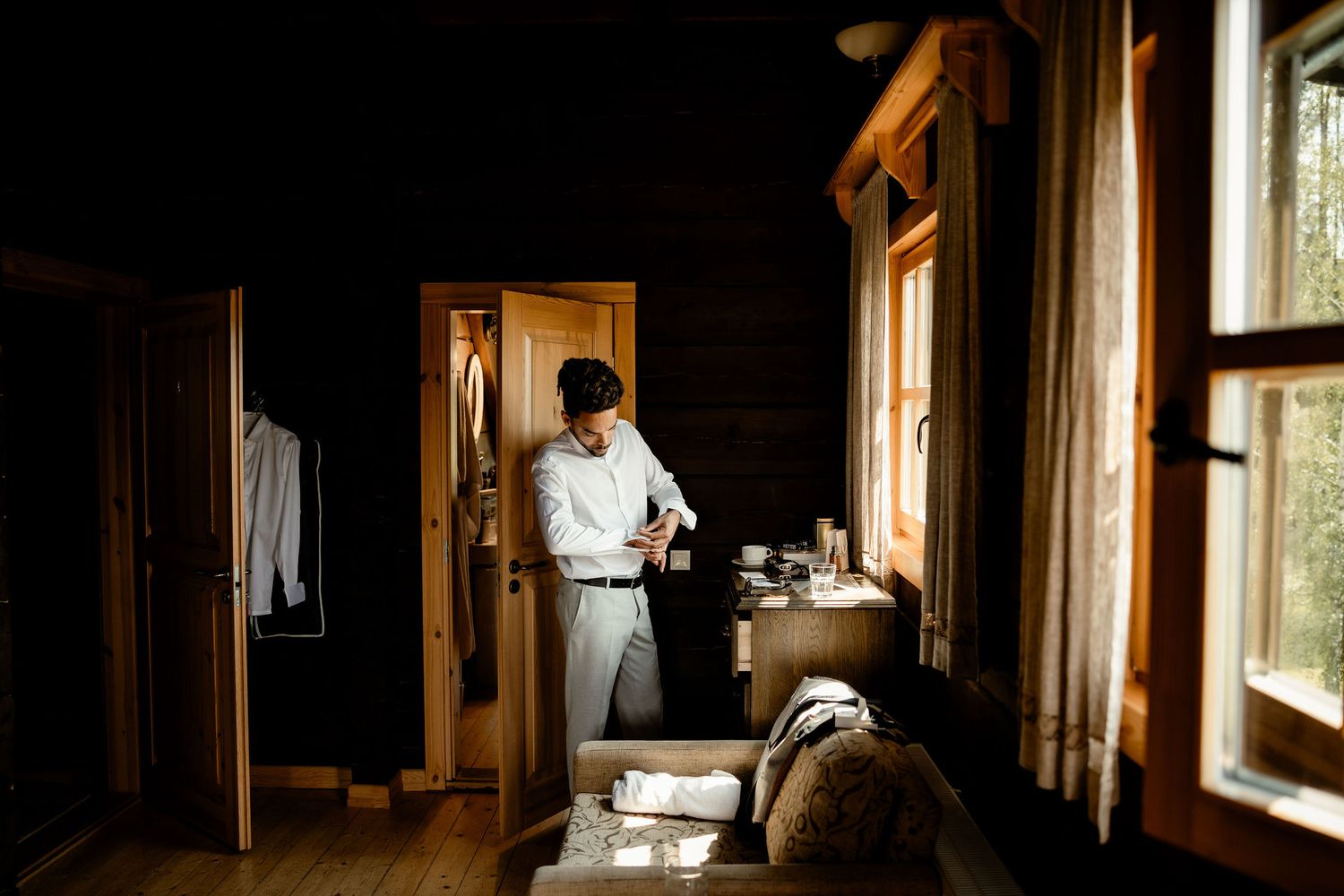 Getting ready in a rustic cabin interior with warm sunlight streaming through windows.
