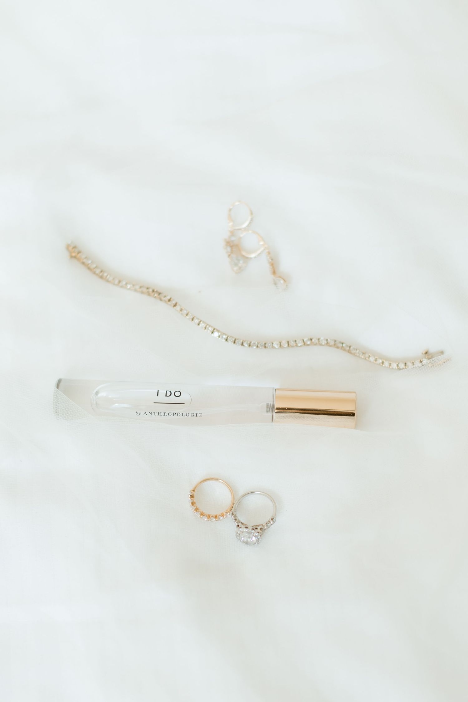 Delicate gold and silver jewelry pieces including rings and a necklace displayed on white marble surface.