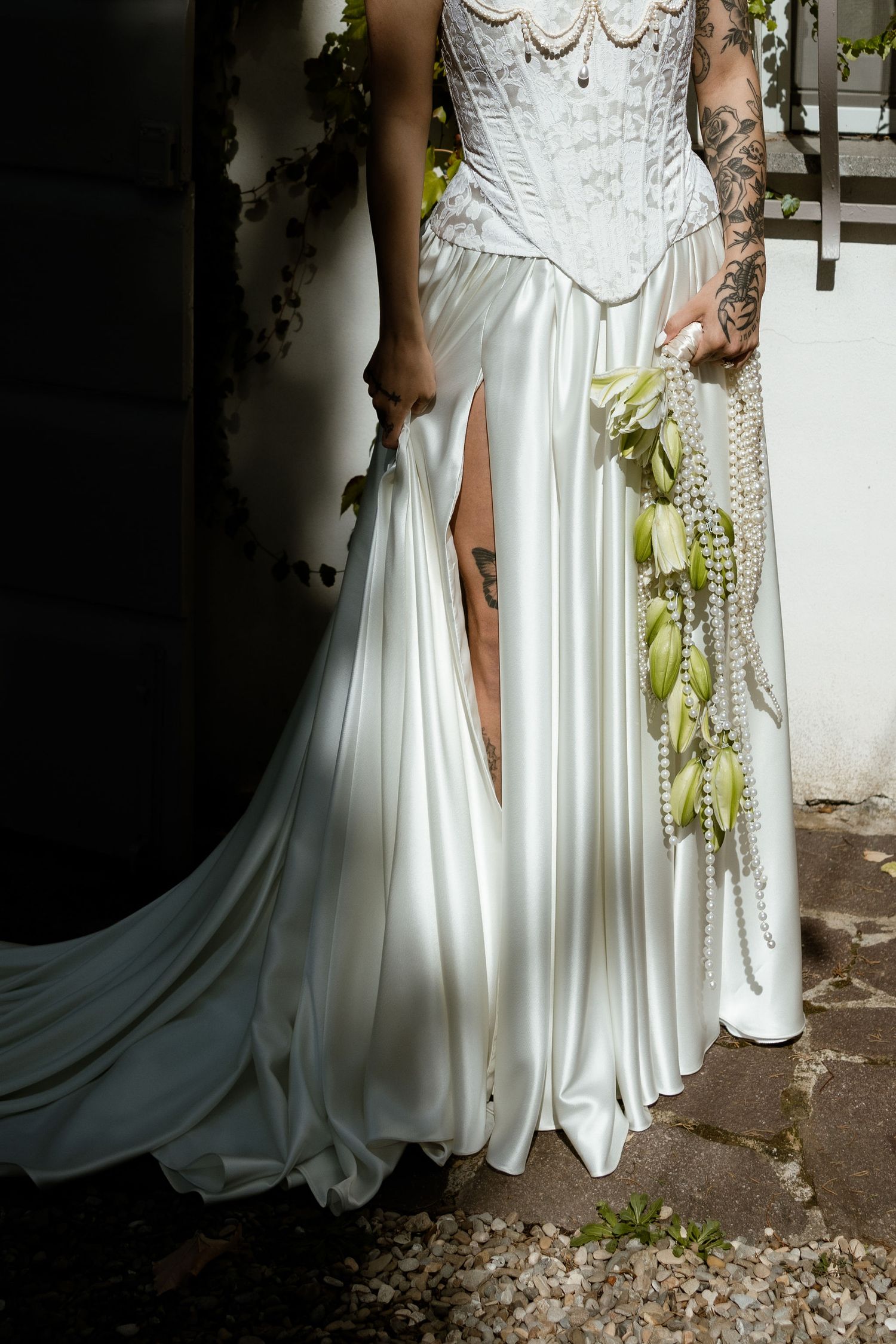 Two people in elegant white wedding dresses stand together against a light background with trailing fabric details.