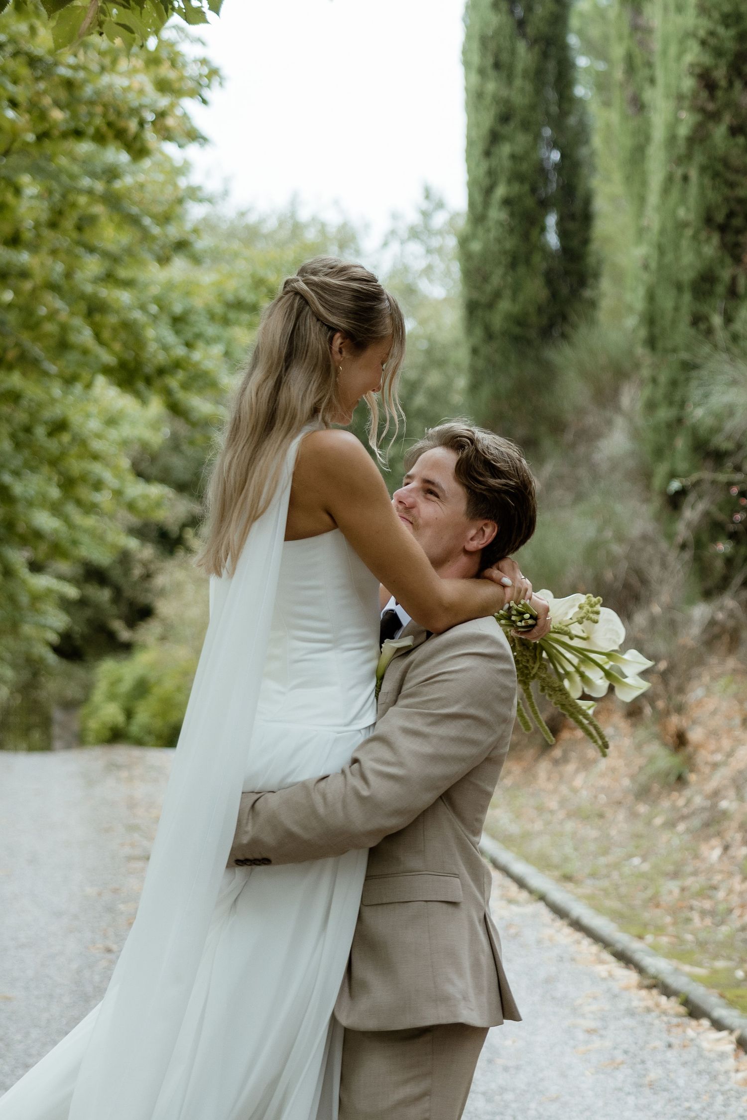 A romantic wedding moment captured in a series of four photos showing a couple embracing on a tree-lined path.