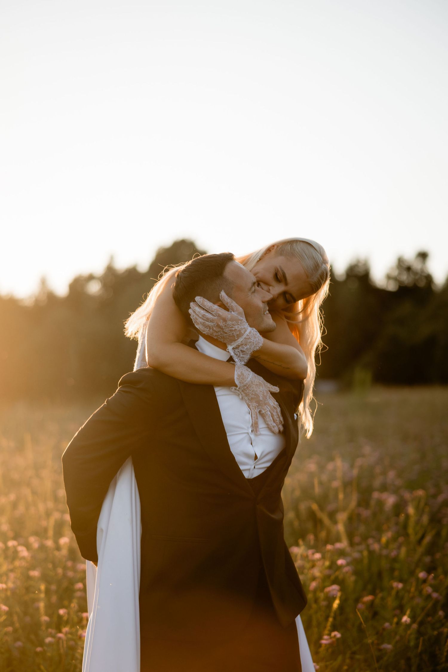 A dip kiss between newlyweds in a sunlit meadow during golden hour.