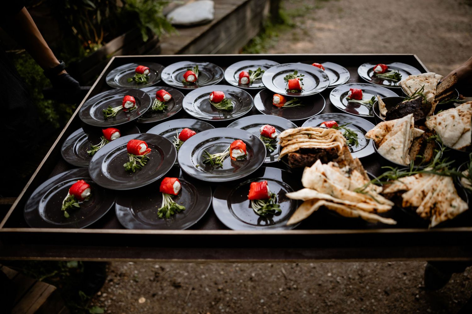 Elegantly plated appetizers on black plates with decorative garnishes.