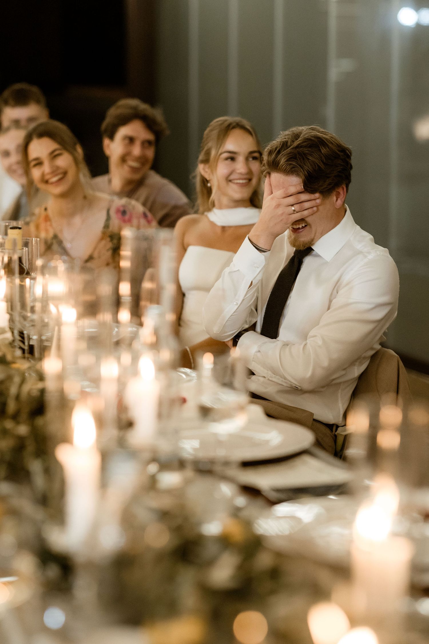 Candlelit dinner table with guests sharing laughter and joyful moments during an evening celebration.