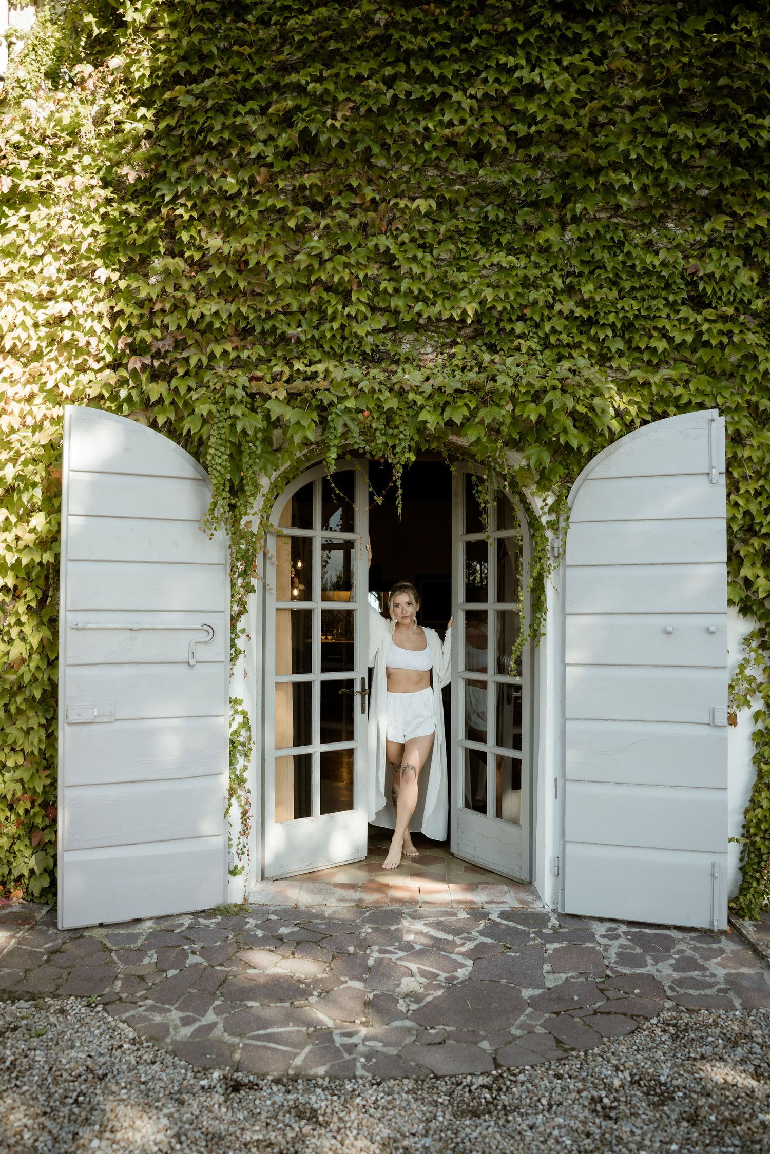 A sequence of four images showing a white door opening gradually with ivy growing above it in a stone wall.