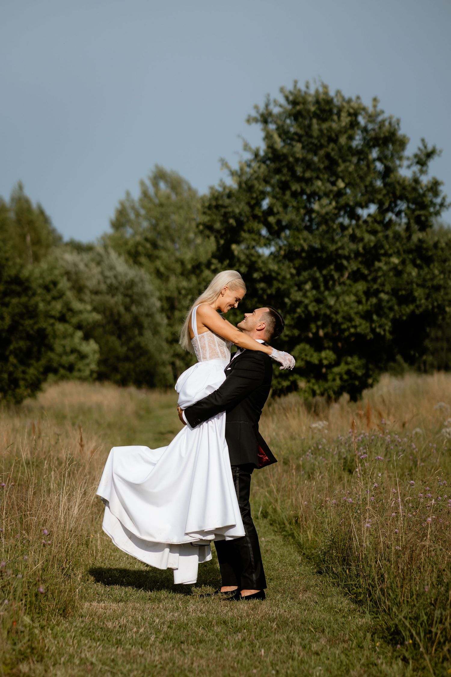 Romantic outdoor wedding portrait showing couple embracing in a field.