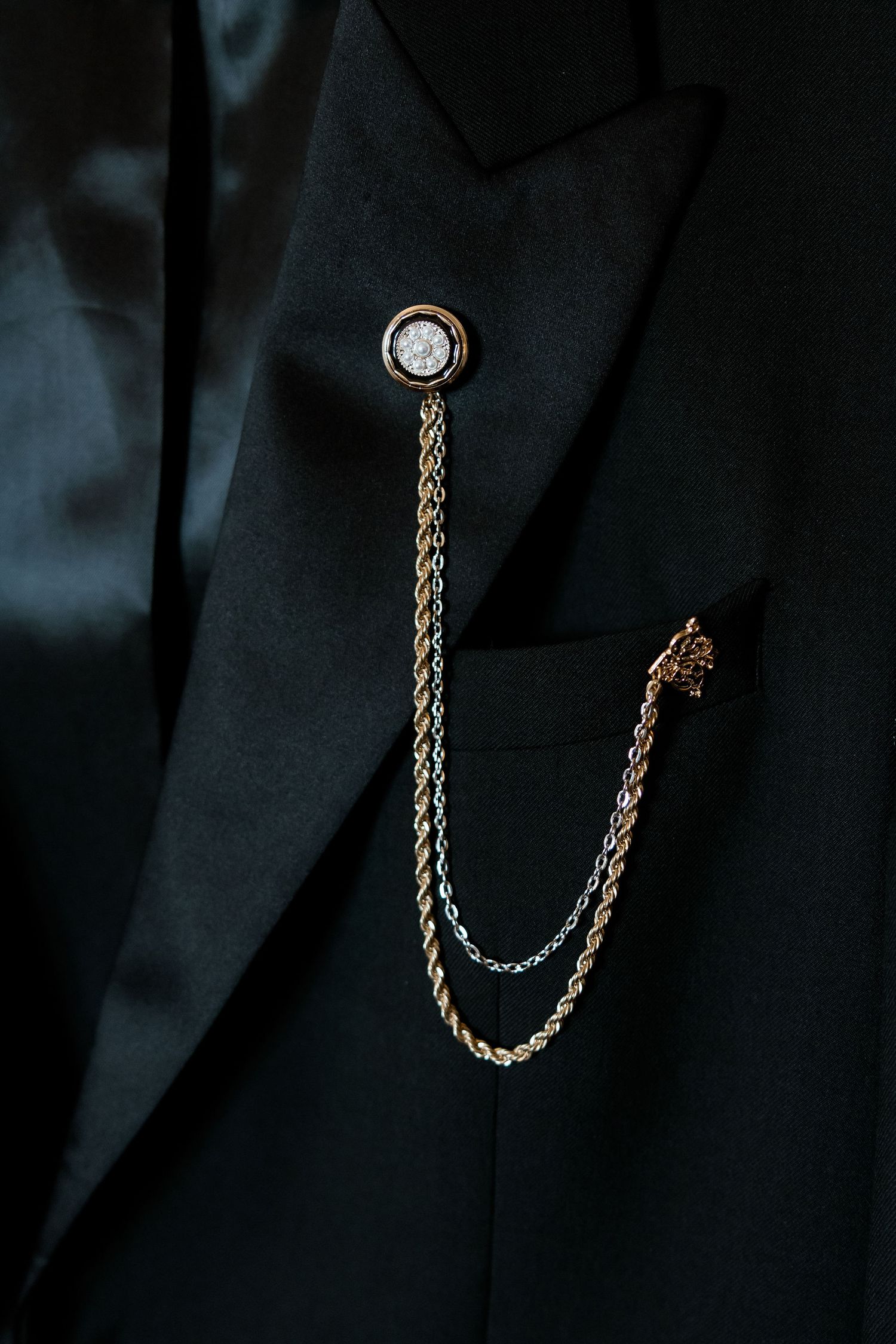 A vintage gold pocket watch chain photographed in dramatic lighting against a dark background.